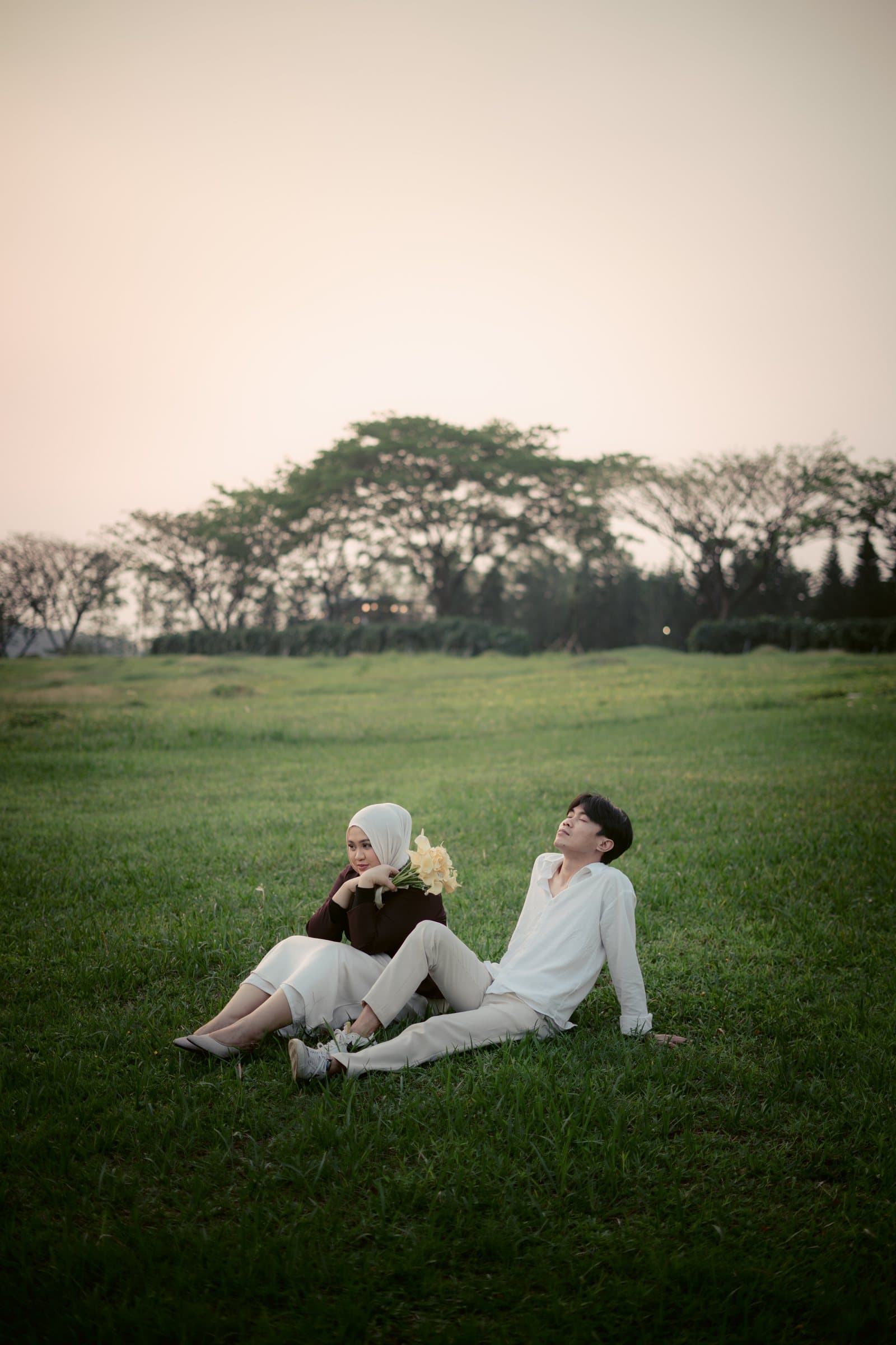 Laras dan Kiki duduk berdua di padang rumput saat golden hour